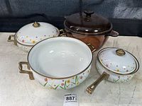 Overall view of 4-piece floral metal pan set with brass handles and lids, plus brown Pyrex Visions pot with lid.