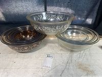 Overall view of two nested Pyrex bowl sets and one single large bowl on top, showing difference in color and patterns.