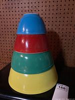 Stacked view of four Pyrex mixing bowls in primary colors - blue, red, green, yellow showing nesting capability.