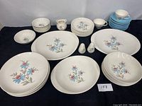 Full display of Steubenville Fairlane dish set with plates, platters, bowls, cups with saucers, creamer, salt and pepper shakers on black cloth background.