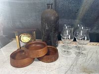 Overview showing wooden bowls, brass clock, glasses, and apothecary jug.