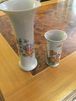 Photo showing two Rosenthal porcelain vases on a wooden table; the larger one has a floral design and the smaller one a child figure design.