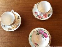 Top view showing 3 cups and their matching saucers with floral designs and gold trim