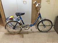 Side view of blue Tornoswheel collapsible bike showing frame, saddle, wheels, and handlebar details
