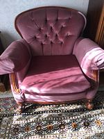 Front view of rose velvet Chesterfield armchair with carved solid walnut wooden frame, visible armrests and seat cushion, positioned on patterned rug.