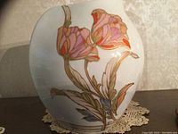 Photo of vase front showing hand-painted floral design with pink, purple and gold colors on white porcelain.