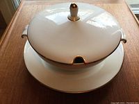 Closed 10-inch soup tureen with lid showing gold trim and side handles on 12-inch platter.