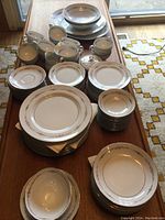 Full view of Mikasa china dinnerware set on table, showing stacked plates, bowls, cups, saucers, creamer, and sugar bowl with lid