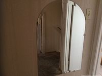 Photo shows a rectangular mirror with beveled edges mounted on a wall near a door frame and light switch. The mirror is clear and free of visible damage.