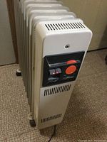Front view of white DeLonghi oil heater showing control panel with red power switch and orange thermostat dial.
