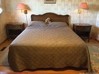 Front view of queen size bed setup showing headboard, side rails, and two nightstands under wall lamps