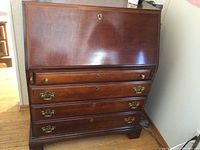 Side view of closed walnut secretary desk with brass handles on drawers