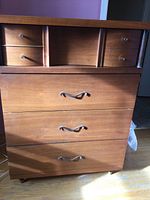 Front view of the walnut veneer tall boy dresser showing the four drawers with metal handles and two small upper drawers with open central space.