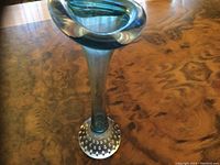 Tall Venetian hand blown glass vase with blue stem and flared rounded top, sitting on a bubble patterned clear glass round base on wooden surface.