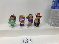 Photo showing the front view of all 4 small Cabbage Patch Kids figurines next to a water bottle for scale.