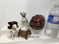 Group shot of four dog figurines and one piggy bank with water bottle for size reference marked as lot 128