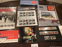 Photo showing seven Canadian stamp booklets and sheets with various themes including military parade, Empress of Ireland, farm tractors, and 1964 commemorative edition.
