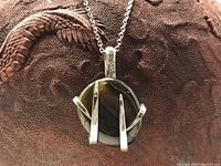 Close-up of the pendant showing the polished oval stone with three silver-tone prongs and part of the chain.