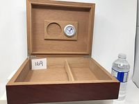 Open wooden humidor box showing inside with divider and hygrometer mounted on the lid.