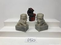 Front view of two Japanese foo dog statues and one resin dragon figurine.