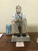 Front view of the large seated old man porcelain figurine with soda can for scale