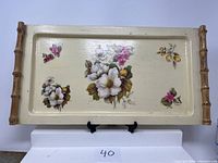 Front view of metal decorative serving tray showing floral design and bamboo handles
