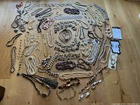 Overview of entire assortment of magnetic jewelry laid out on wooden surface showing necklaces, bracelets and earrings in multiple colors and styles.
