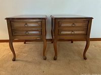 Front view of the pair of wooden end tables showing two drawers each with metal ring pulls.