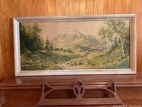 Full view of the framed art showing the entire mountain and sheep scene with wooden frame.