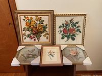 Set of five framed floral art pieces arranged together showing variety of art styles and frames.