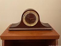 Front view of vintage wooden mantel clock showing overall shape and condition.