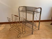 Two metal stands for holding records or magazines, one larger with two shelves and one smaller with wooden handle.