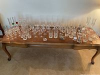 Wide view of entire collection showing multiple rows of clear crystal glassware including stemmed glasses, tumblers, chimps glasses, along with some colorful decorative elements.