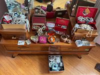 Wide shot of multiple open jewelry boxes and loose pieces spread on a wooden table.