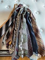 Photo showing a collection of neck ties featuring various stripes, geometric, and paisley patterns in shades of beige, navy, grey, and other colors.