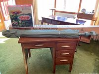 Photo showing green patio umbrella folded and resting on a wooden desk indoors.