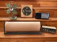 Full lot view showing all items on wooden shelf: fan, clock, radios, and fluorescent light