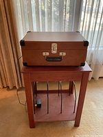 Record player in closed position on wooden stand, showing overall size and setting.