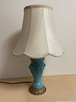 Full view of the blue ceramic table lamp with cream fabric shade, showing the overall shape and design