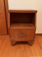 Front angle showing the cabinet's single drawer with handle, open shelf above, and angled legs