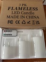 Closed cardboard box labeled '3 PK FLAMELESS LED Candle Made in China' with remote control and one LED candle visible in styrofoam packaging.