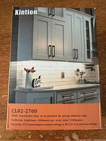 Photo of Kintion branding and product information on the front of the box showing easy adhesive tape installation, 280 lumen per strip brightness, 1100 lumen total output, DC 12V low voltage safe power adaptor included.