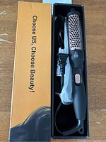 Top view of the curling iron brush in original box, showing the device, power cord, and packaging.