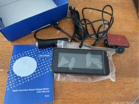 Multi-function smart slope meter with accessories including mount, car adaptors, and user manual in packaging.