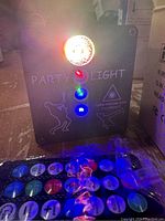 Front view of the party light powered on, showing the colored LED lights and control buttons with light patterns projected on background.