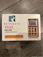 Front of the radio box shows brand name Retrakess, model V112, FM/AM 2 band stereo radio, DSP, ATS presets, LED and headphone icon.