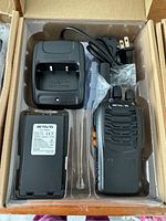 Contents inside original box showing Retevis branded radio, charger base, battery, and power cord wrapped in plastic