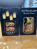 Boxes of Solar Mason Jar Lights showing the front and side with product images and text.