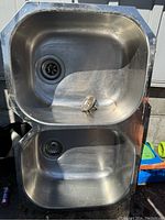 Top-down photo showing the two undermount stainless steel sink basins with drain holes and stoppers inside.