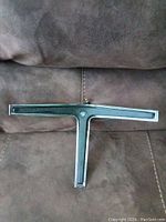 Chrome T-shaped horn switch with center circular button from 1967 Buick Riviera, showing front face and T-bar design.